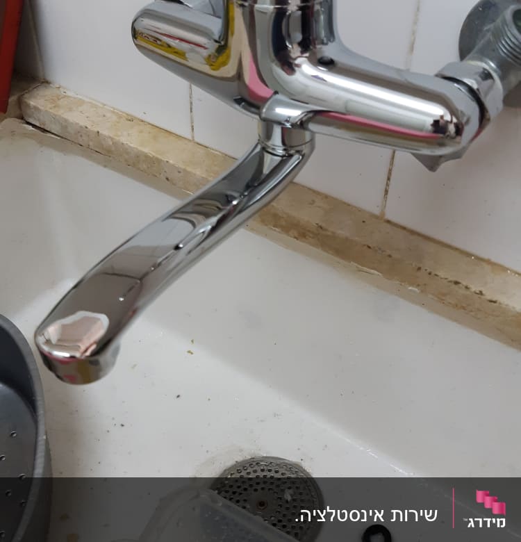 ברז כרום מעל כיור עם מים עכורים